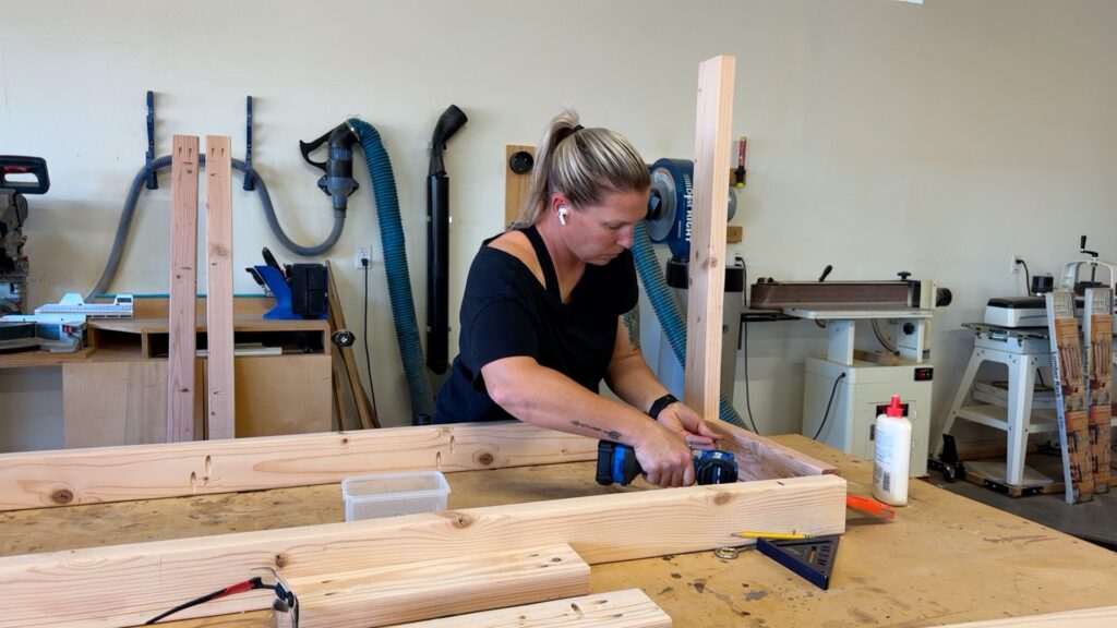 Assembling the wooden frame of a DIY mobile workbench using screws and pocket hole joinery.