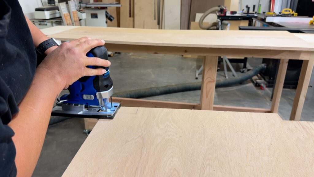 Using a jigsaw to cut notches in plywood to fit around the workbench frame supports.