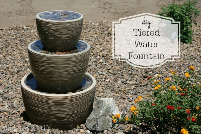 DIY tiered water fountain made with stacked pots in a desert courtyard with decorative rock landscaping