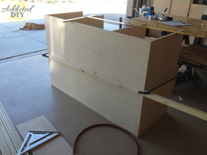 Attaching the back panel to the plywood kitchen island base during cabinet assembly