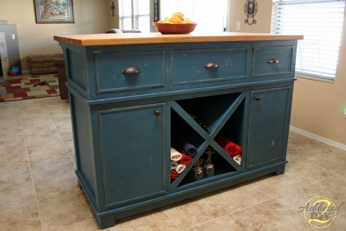 Back view of finished DIY kitchen island with corbels, overhang seating area, and metal bar stools