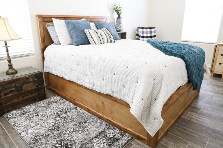 Finished DIY queen size storage bed in guest bedroom with wood frame and headboard