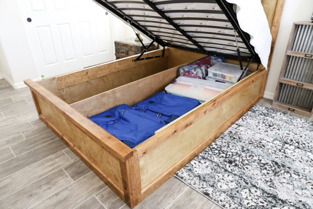 Open queen platform storage bed showing large hidden compartment for totes and luggage