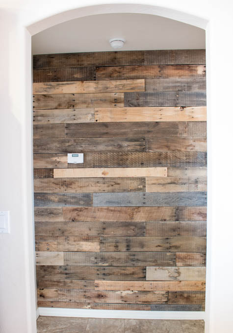Completed pallet wood accent wall in hallway with mixed wood tones and staggered pattern