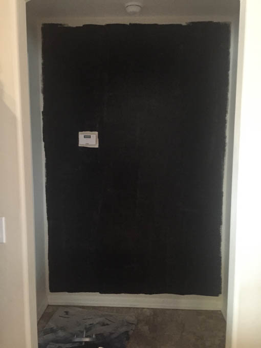Wall painted black as a base layer before installing wood planks