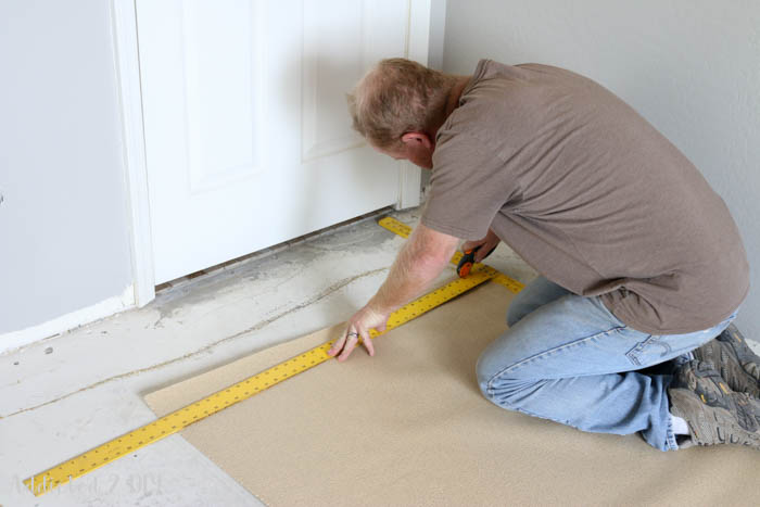 Measuring and cutting flooring underlayment on concrete subfloor before laminate floor installation