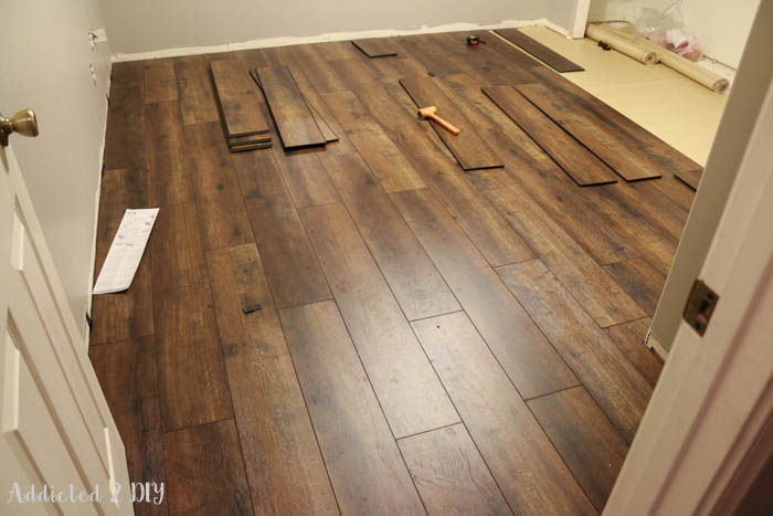 Installing laminate wood flooring planks over underlayment with staggered layout during DIY floor project