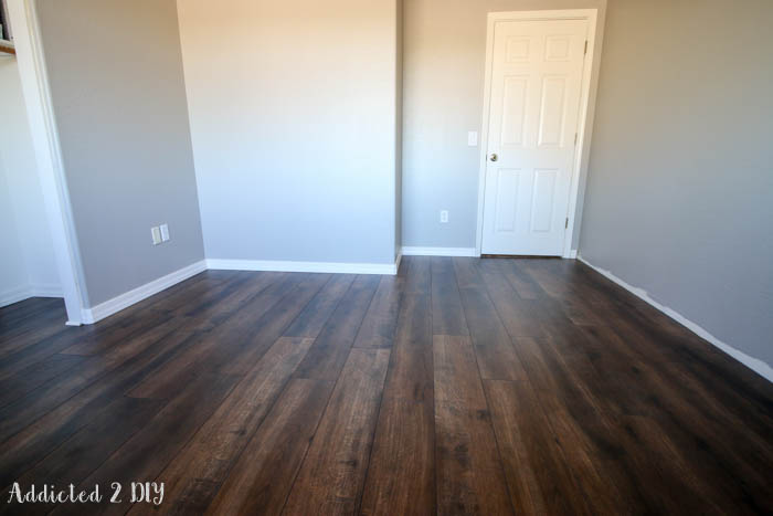 Finished laminate wood flooring installed in room with gray walls and white trim modern farmhouse style
