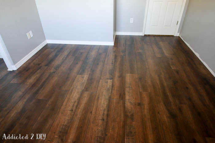 Finished laminate wood flooring installed in room with gray walls and white trim modern farmhouse style