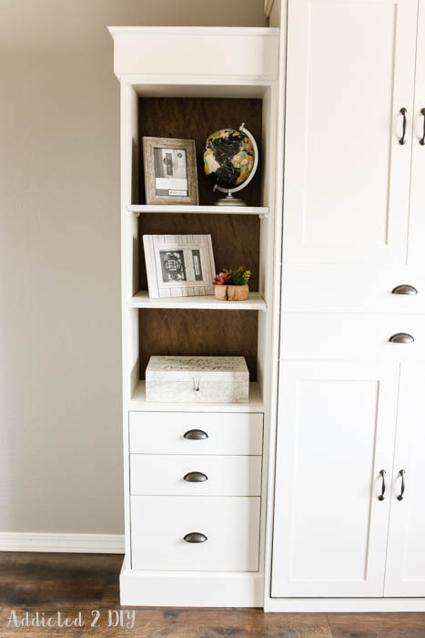 Built-in bookcase with drawers next to DIY Murphy bed showing storage and decor styling