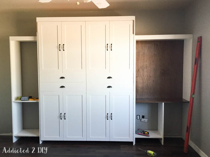 Murphy bed and bookcase installation in progress with tools and level visible