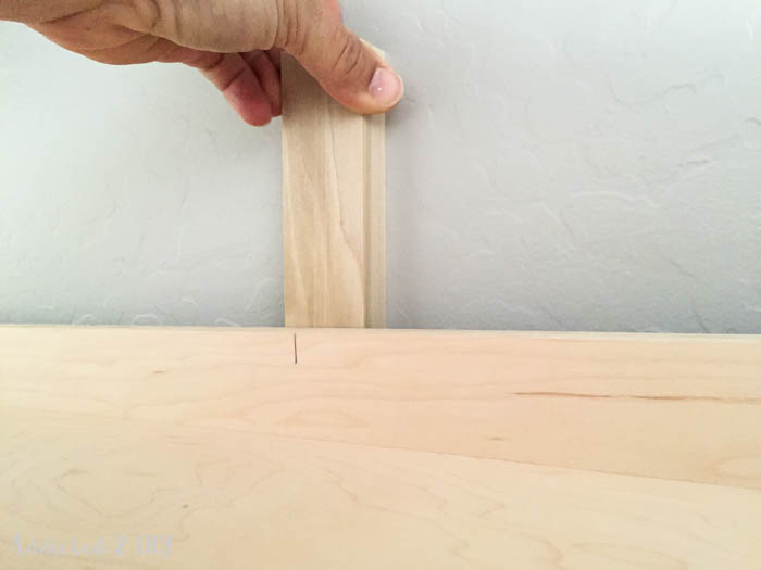 Inserting shims between wall and Murphy bed before securing to the wall with lag bolts