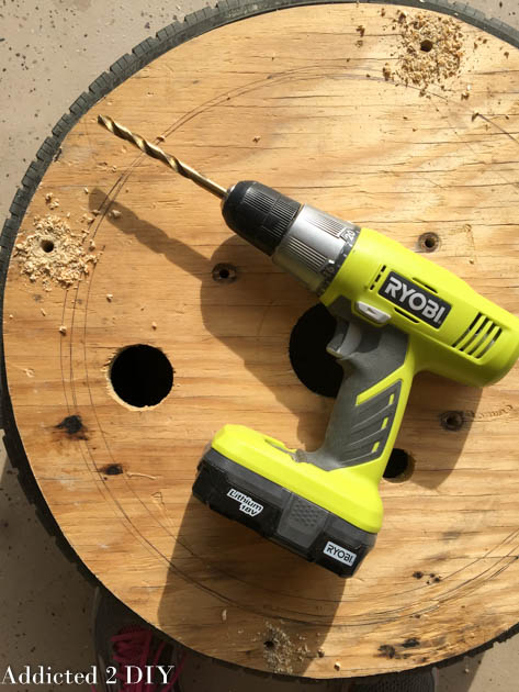 Drilling holes through the wood base and tire for the DIY planter assembly