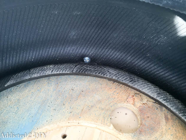 Bolt pushed through the tire sidewall and wood base during tire planter assembly