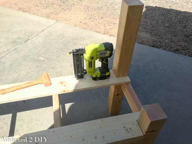 Seat board being attached to the bench frame with a Ryobi brad nailer during assembly.