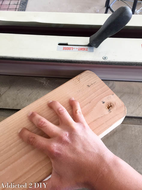 Hand rounding over the edge of a wooden armrest on a router table for a smoother finished shape.