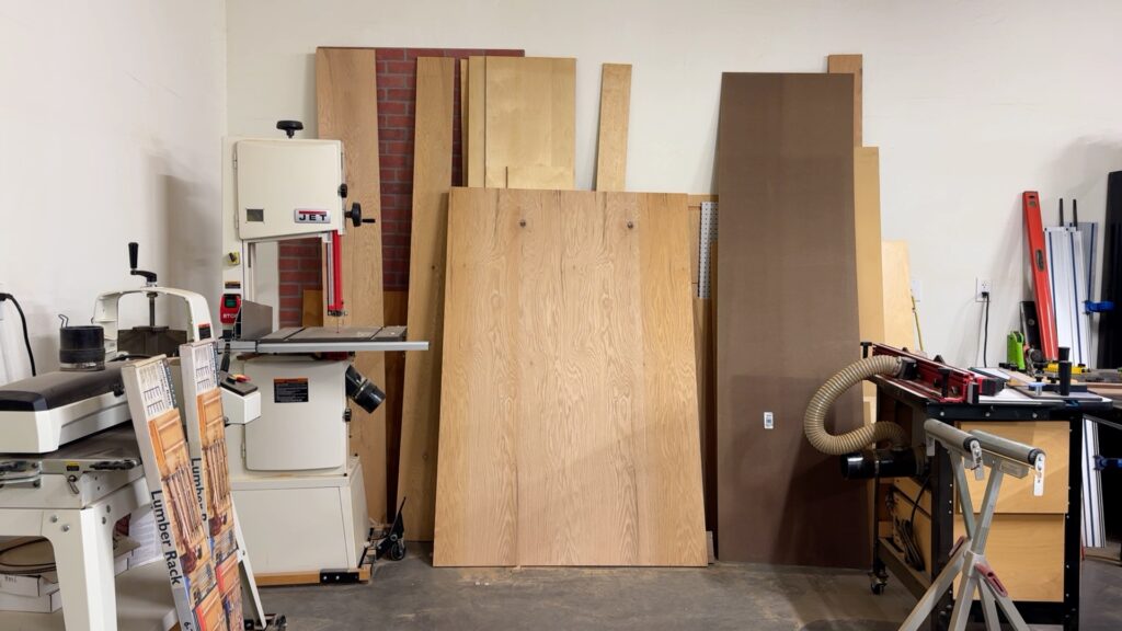 Stack of plywood sheets and wood panels ready for cutting in a woodworking shop.