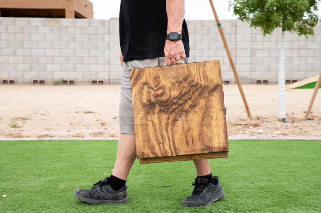 man carrying a washer toss game by handles