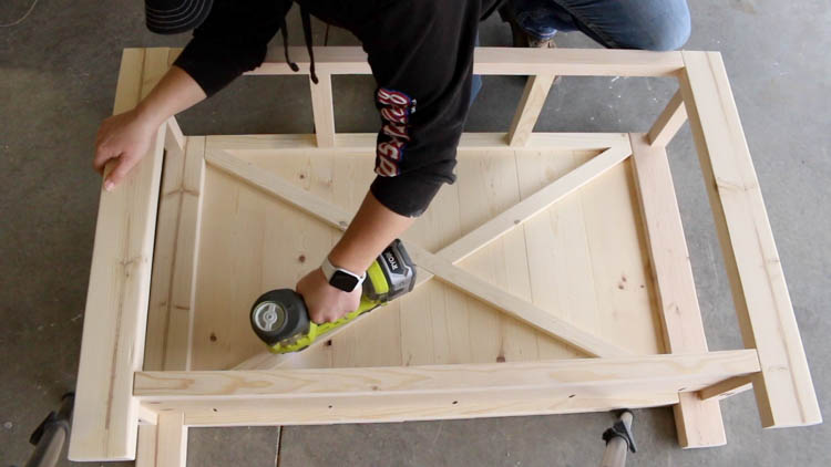 Attaching decorative X detail to back panel of DIY farmhouse console table with brad nailer