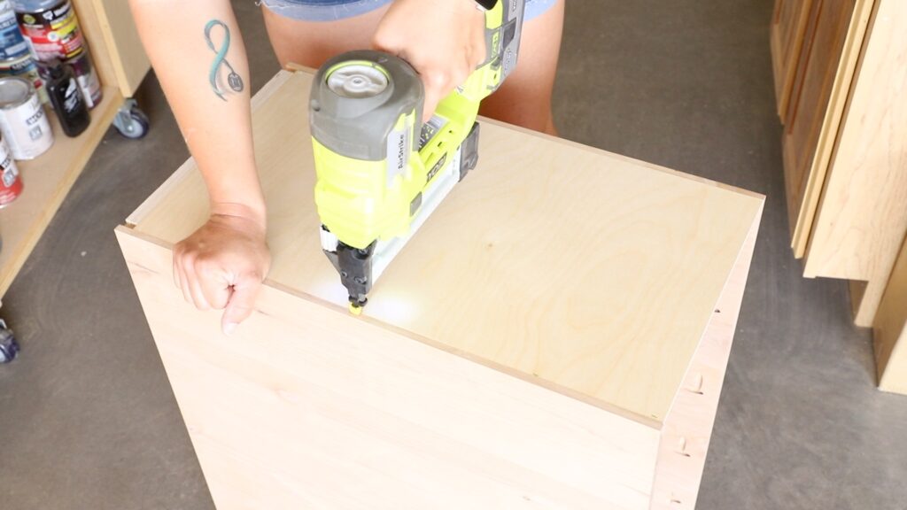 Attaching a plywood back panel to a DIY desk cabinet using a nail gun