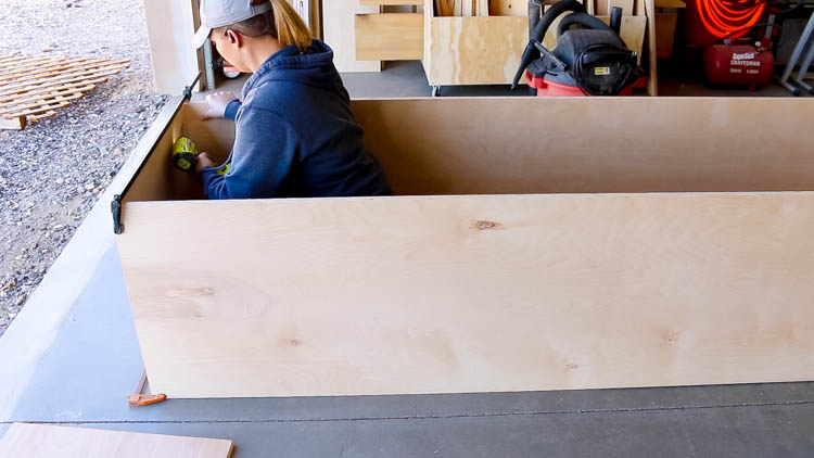 Attaching the end panels of a DIY miter saw bench carcass with a pocket hole jig and drill
