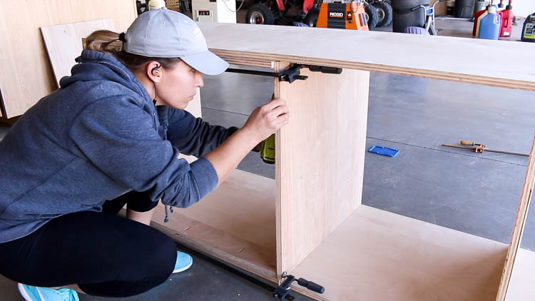 Attaching the end panels of a DIY miter saw bench carcass with a pocket hole jig and drill
