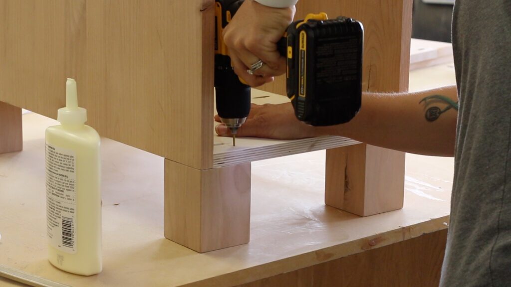 Attaching square wood legs to the bottom of a desk cabinet using glue and screws