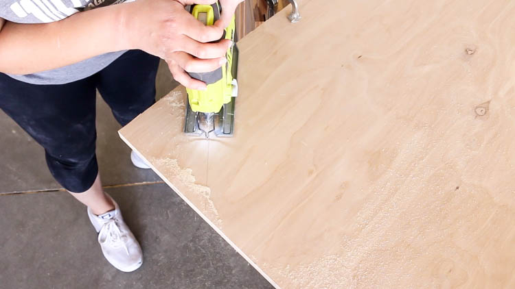 Cutting the front corner off a plywood miter saw bench table top with a jigsaw to allow saw base clearance