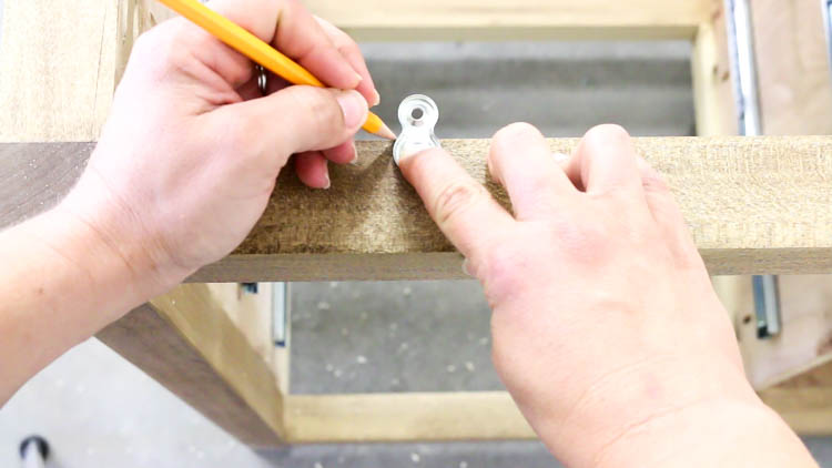 Tracing a desktop fastener with a pencil to mark a recess for flush mounting the dresser top