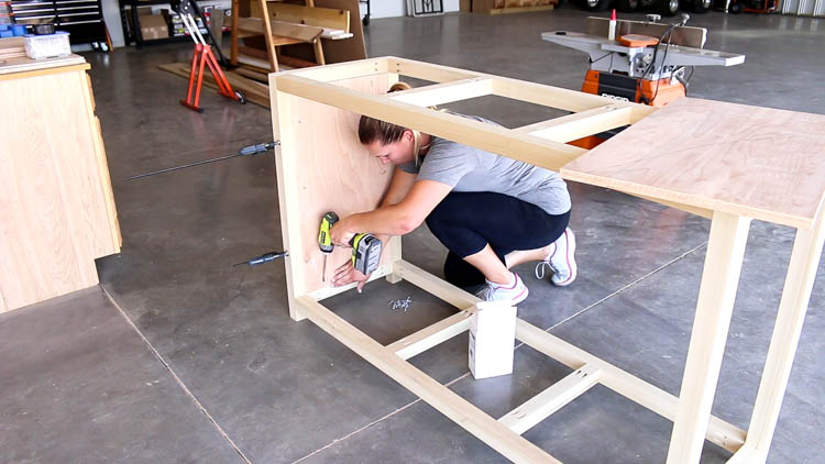 Builder assembling the main 2x2 frame of a DIY rustic dresser with pocket screws and a cordless drill