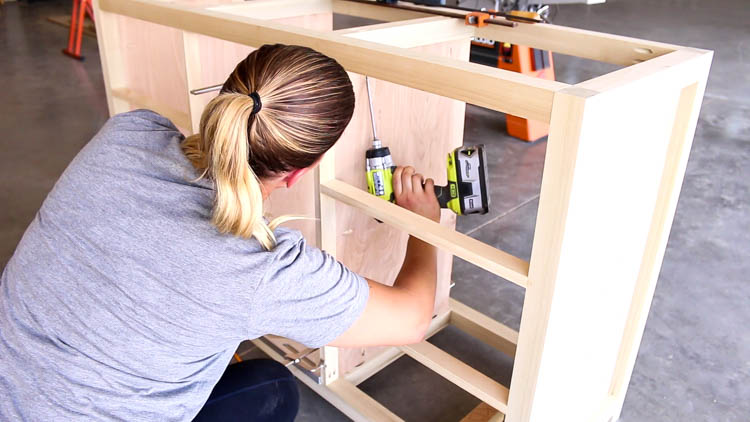 Attaching plywood cabinet walls inside the dresser frame using a Ryobi drill and pocket screws