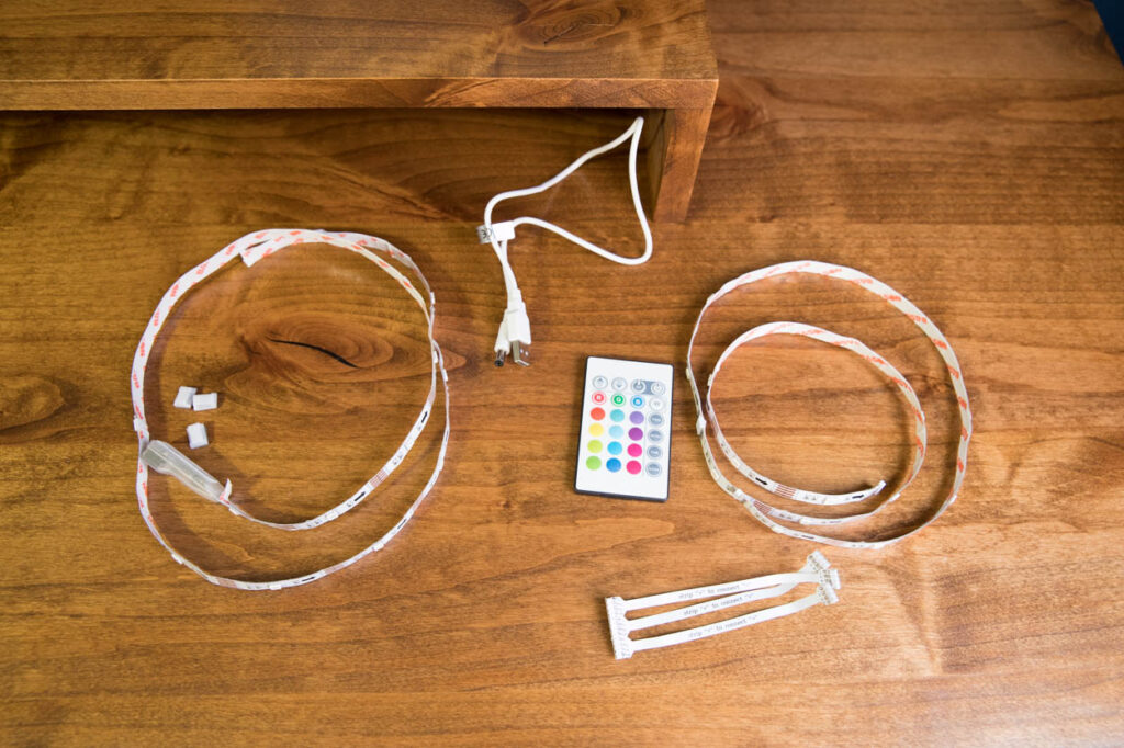 RGB LED strip lights and accessories laid out on a wood desk surface before installation