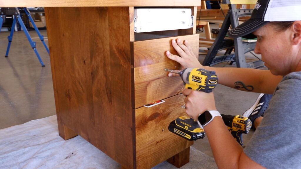 Installing wood drawer faces on a finished stained gaming desk cabinet using a DeWalt drill