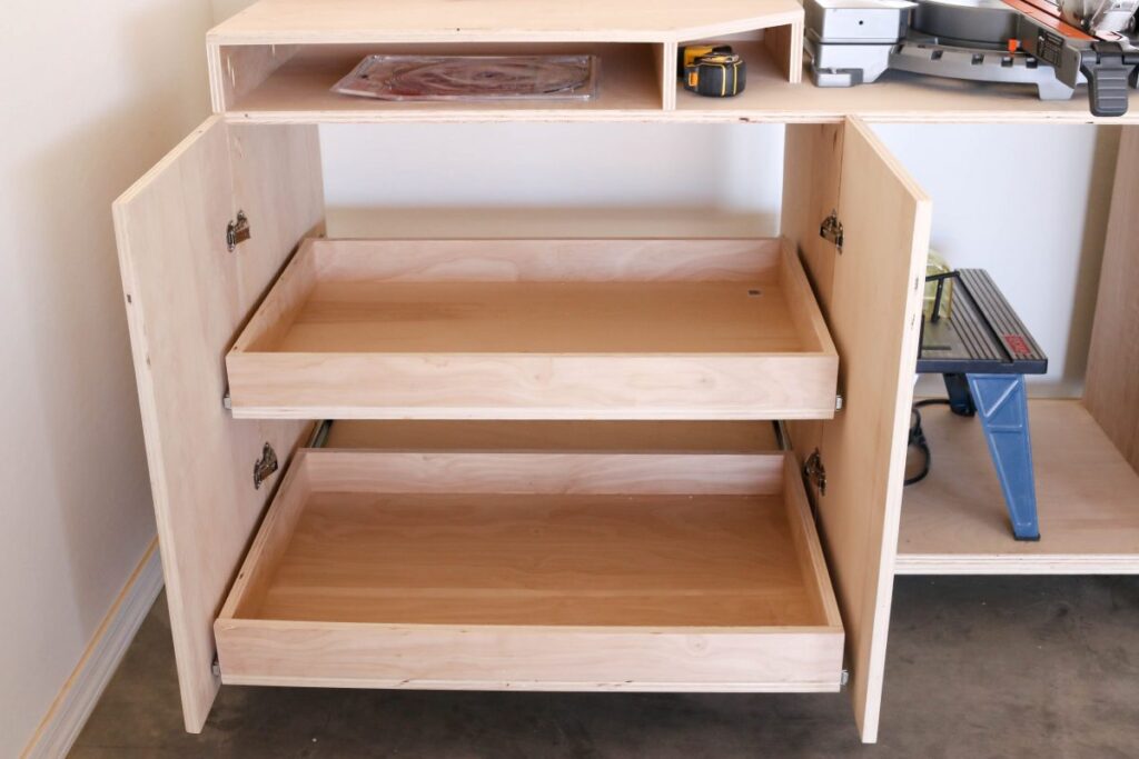Finished DIY miter saw bench cabinets with pull-out shelves fully extended showing tool storage