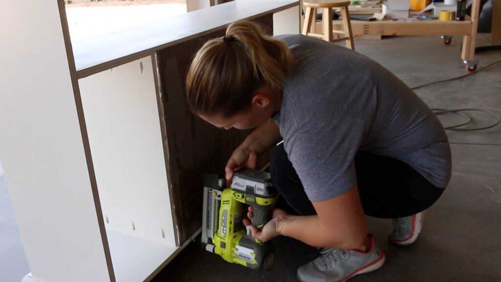 attaching the back panel inside the faux fireplace cabinet with a nailer