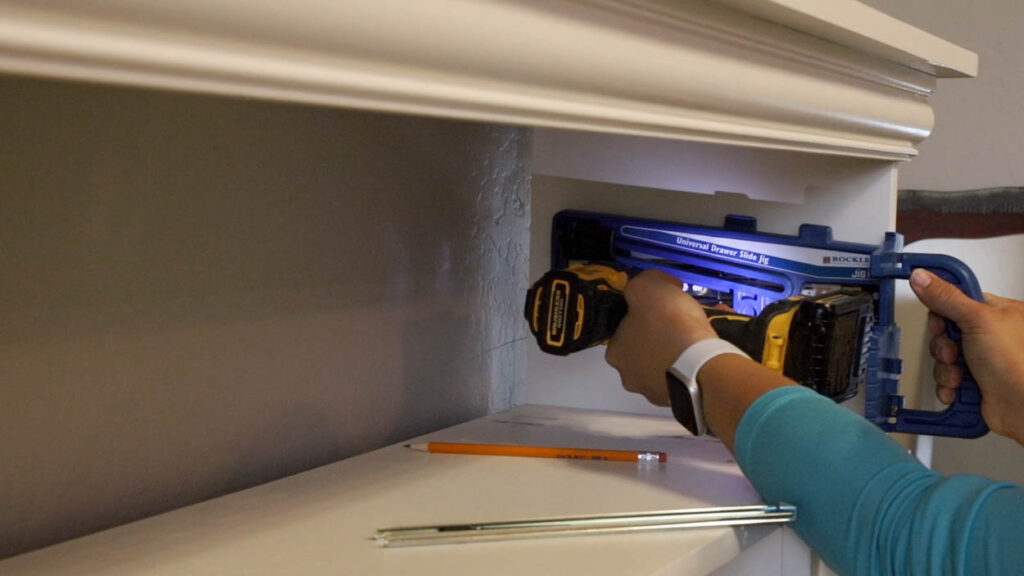 installing drawer slides inside the DIY faux fireplace cabinet opening