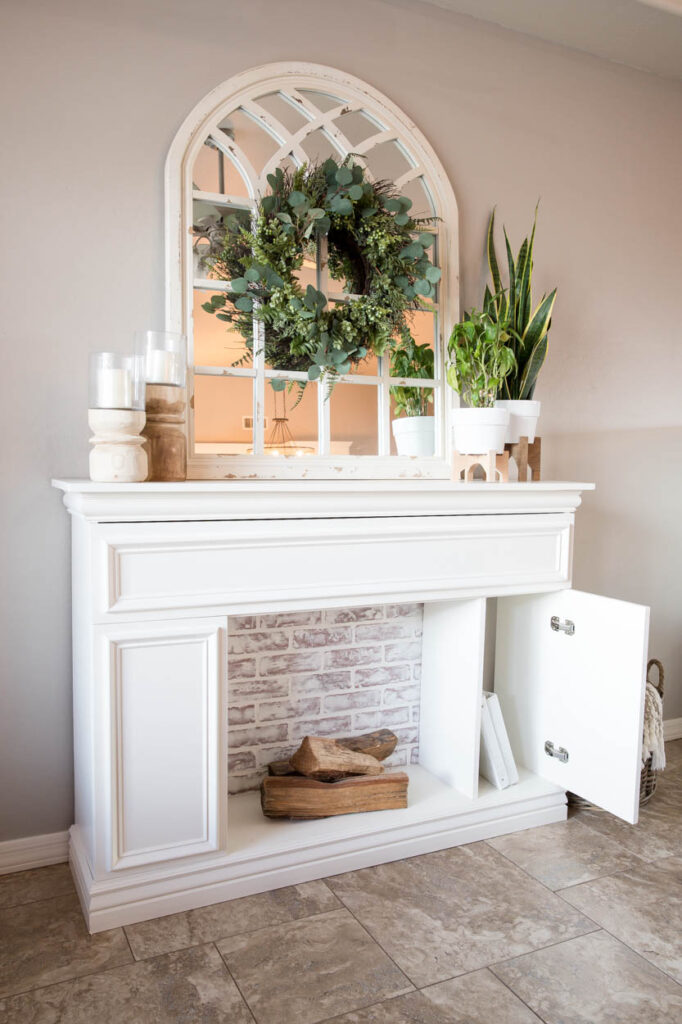 styled mantel on DIY faux fireplace with mirror, wreath, candles, and plants