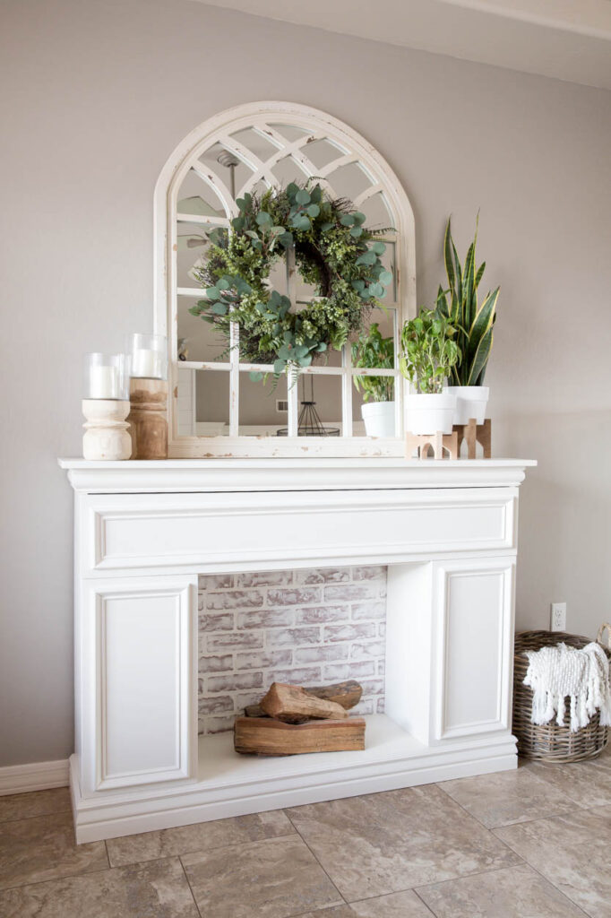 DIY faux fireplace styled in a modern farmhouse look with greenery and mirror