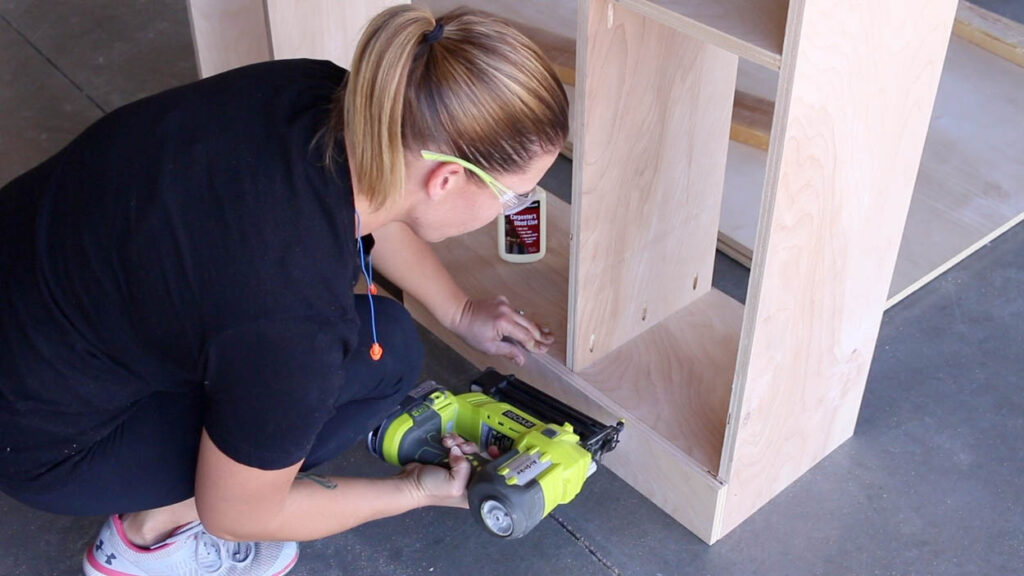securing the bottom panel of the faux fireplace using a brad nailer