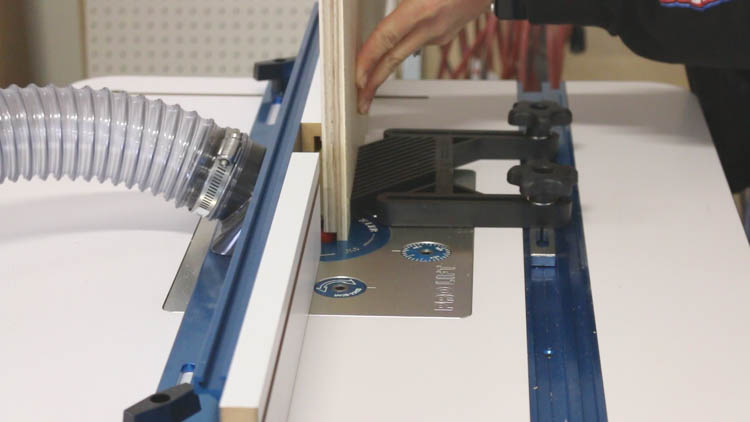Cutting a rabbet groove into plywood on a router table for the back panel of a DIY cabinet