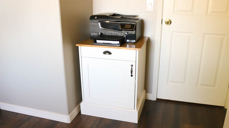 Finished DIY modern farmhouse printer cabinet with white painted base, walnut stained top, cup pull drawer, and inset door installed in a home office corner