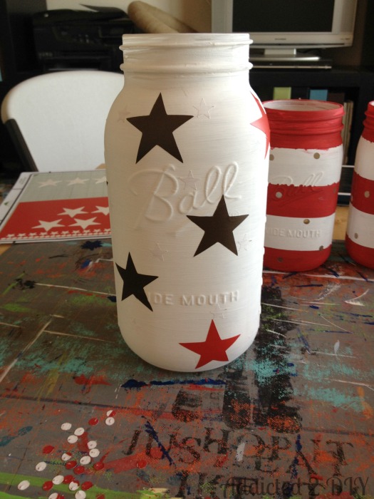 Half-gallon Ball mason jar painted white with large black and red vinyl star decals applied as a paint resist before the blue top coat is added.