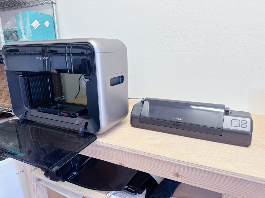 EufyMake E1 UV Printer on work bench with DTF laminator next to it