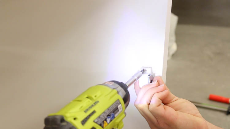Installing a magnetic door catch on the inside edge of a white painted cabinet door with a Ryobi drill