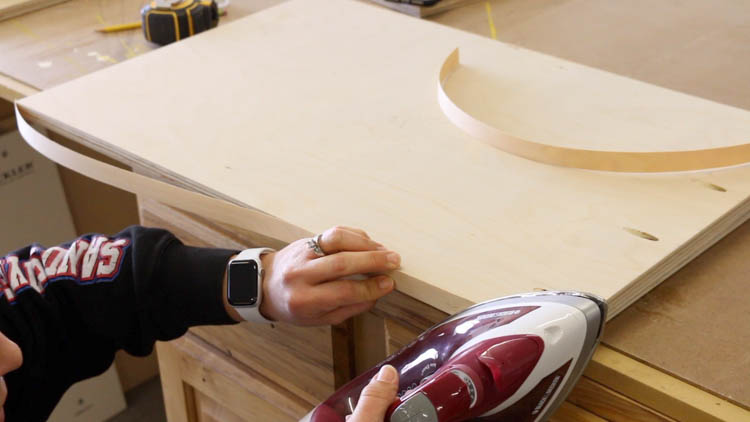 Ironing on iron-on edge banding to the front edge of a plywood panel for a DIY cabinet build