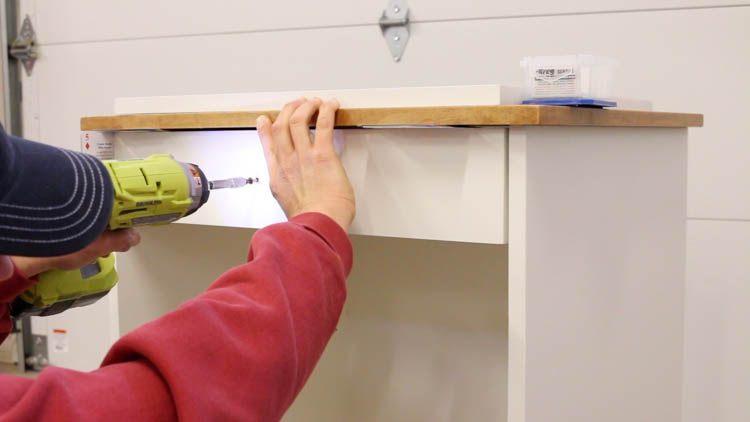 temporarily attaching the drawer front to the printer cabinet with screws
