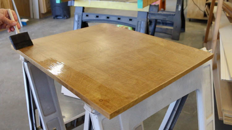 brushing polyurethane onto the stained cabinet top