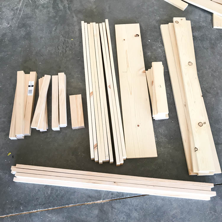 Cut lumber pieces organized on workshop floor for building a DIY storage bench with hidden storage