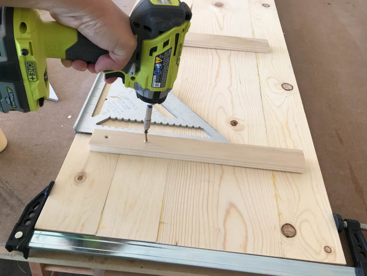 Using a drill to attach support boards to the storage bench lid during assembly