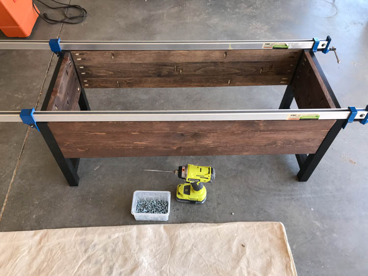 Storage bench frame clamped during final assembly in workshop